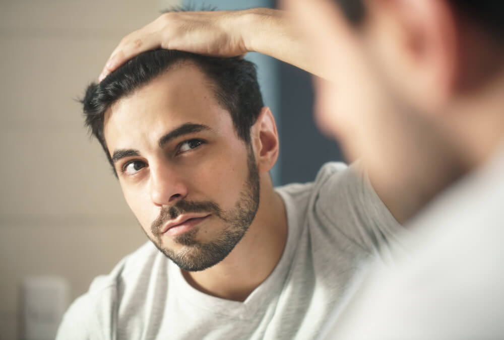 鏡で髪を確認する男性