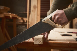 のこぎりで木材を切る男性の手