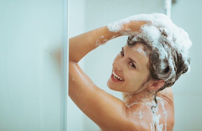 シャワーでシャンプーを流す女性