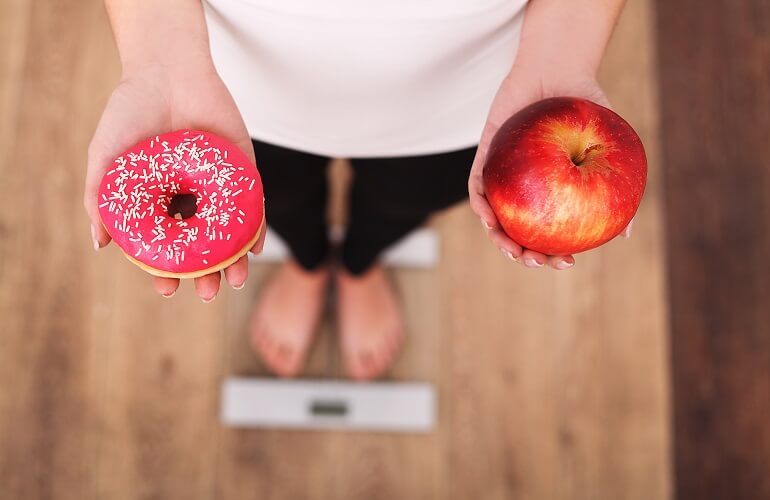 りんごとドーナツを比べる女性